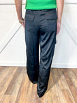 Woman modeling the back of black satin cargo pants with a satin tie belt