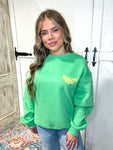Woman modeling our green sweatshirt that says Howdy on the front frocket area