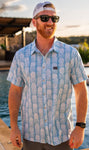 Man modeling our light blue, short sleeve button up shirt featuring white pineapples and has a chest pocket on the right side