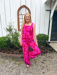 Another photo of a Woman modeling the front of this red with magenta flowers all over matching set which has a tank top and matching elastic pants