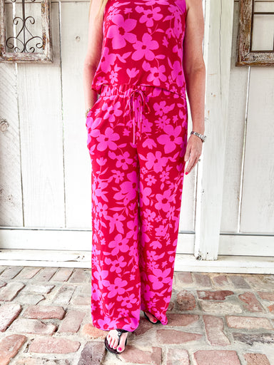 Woman modeling the matching red with magenta flowers all over pants to this matching pants set