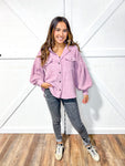Woman wearing a lilac colored corduroy button down shirt or shacket with black jeans and sneakers