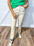 Woman wearing beige pleather pants with a green top and sneakers