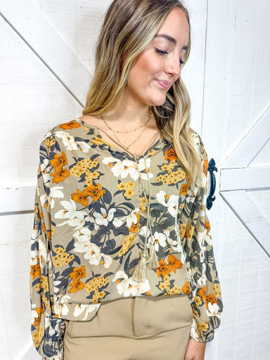 Woman wearing a long-sleeve blouse with flowers in fall colors