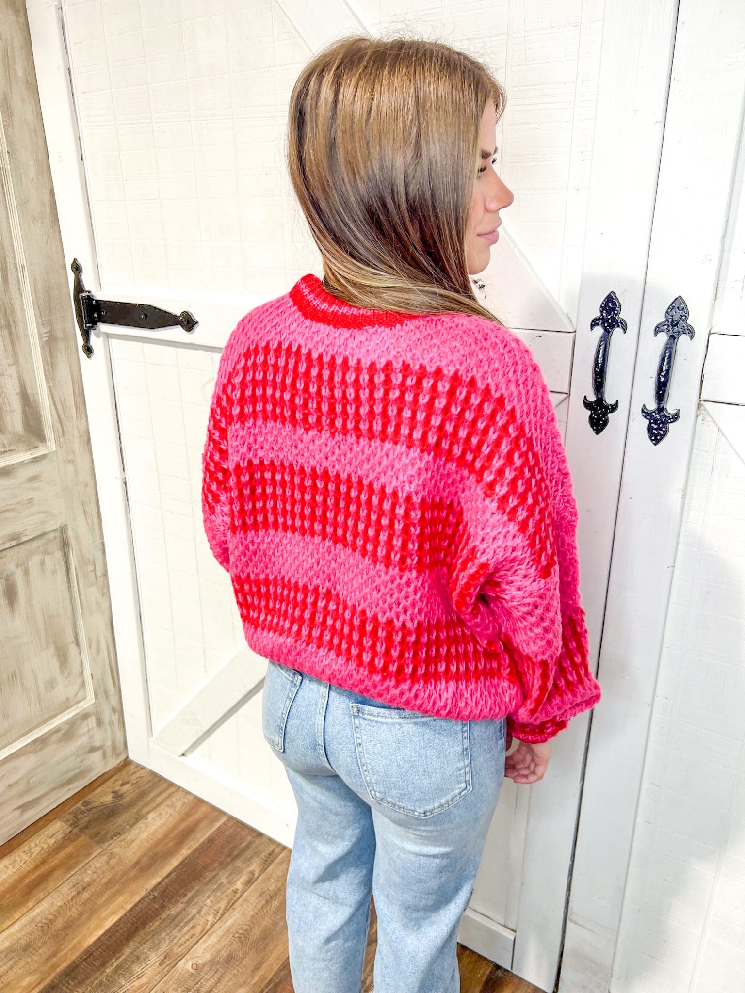 woman wearing a hot pink and red large stripe cable knit crew-neck sweater