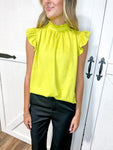 Woman wearing a lime short sleeve blouse with soft ruffle at the sleeve with black pants
