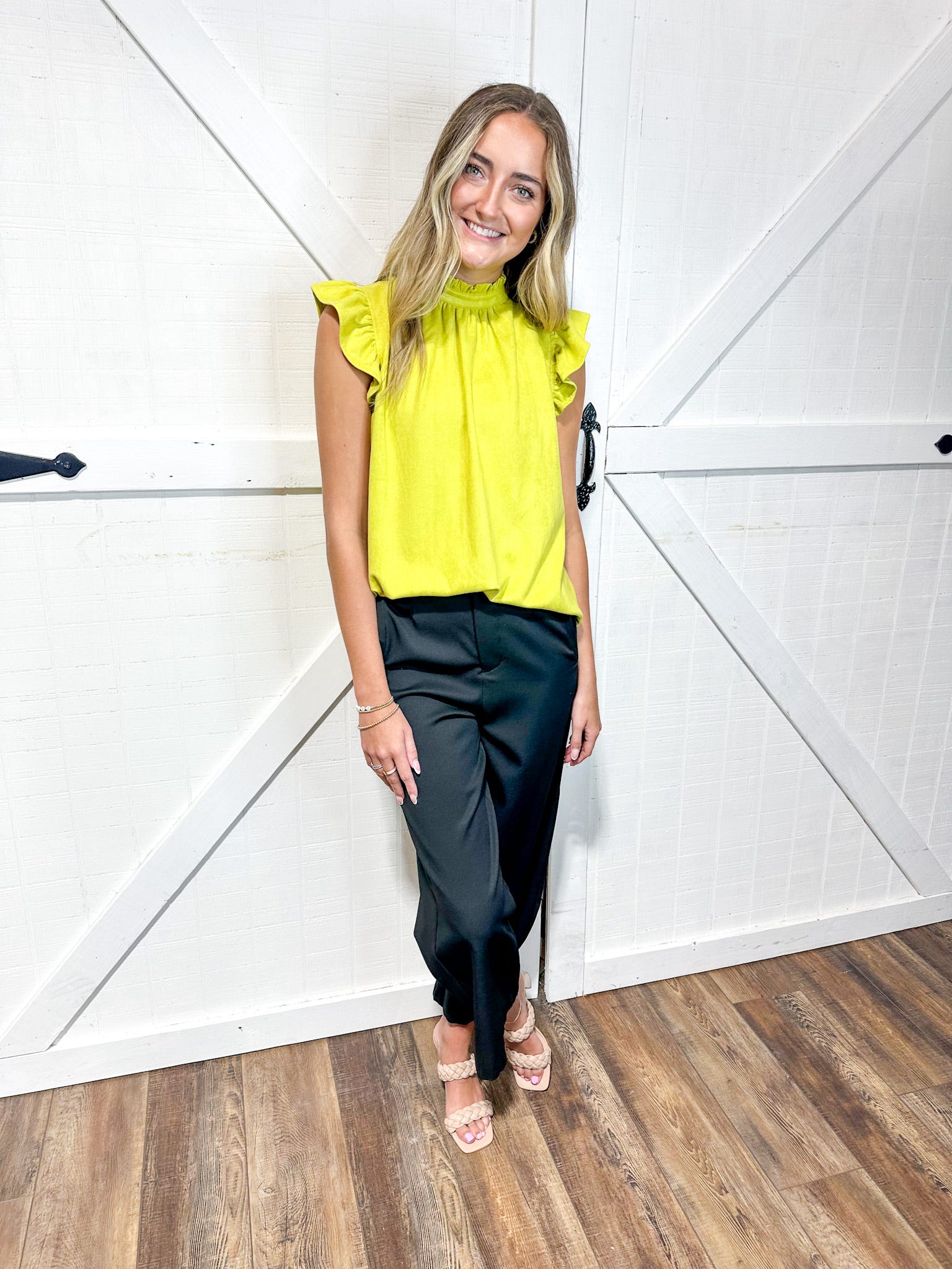 Woman wearing a lime short sleeve blouse with soft ruffle at the sleeve with black pants