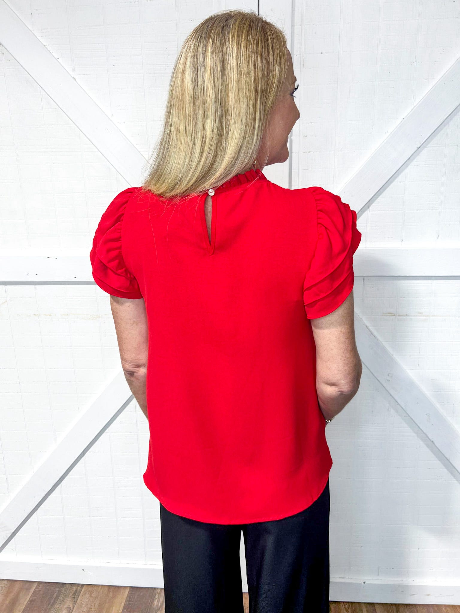 woman wearing a red short sleeve blouse with ruffle detail on the sleeves