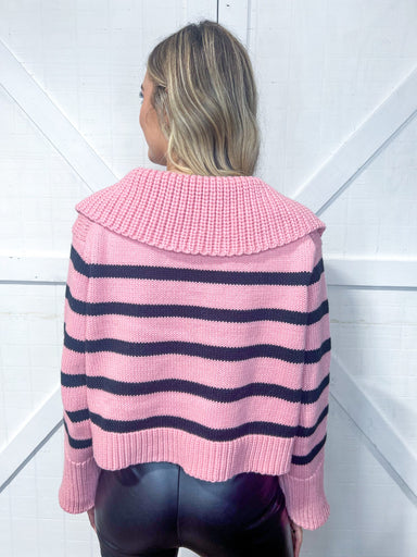 Woman modeling the back of a dusty pink with black stripes sweater with a V-neck and wide collar and sleeves