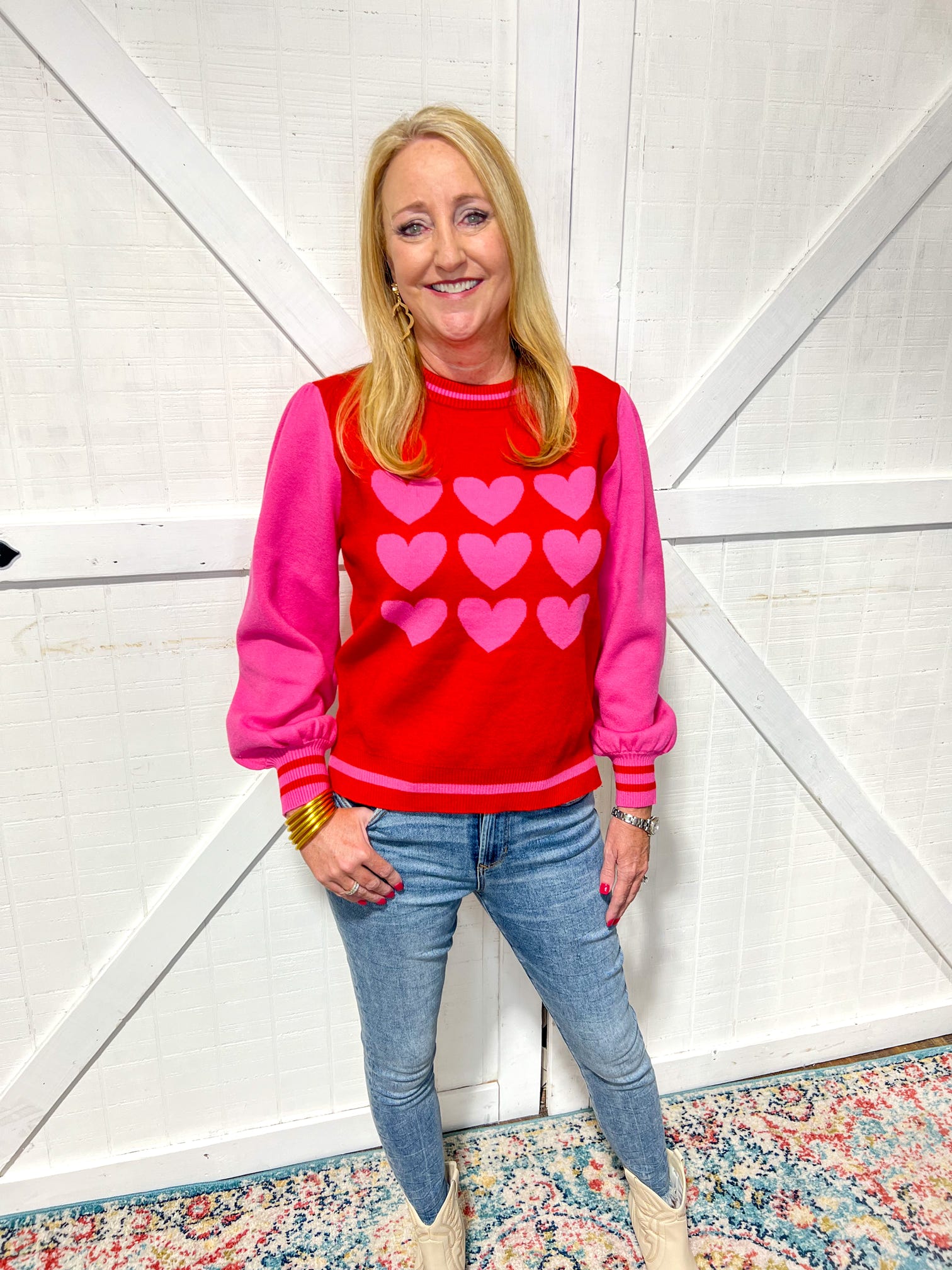 Model wearing a red long sleeve sweater with pink hearts on front and pink sleeves