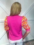Woman modeling a hot pink short sleeve sweater top that has rainbow colored crocheted sleeves