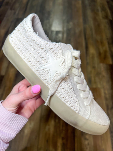 Photo of a beige ‘distressed’ sneaker with crochet material and a beige star.  