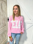 Another view of a woman modeling our light pink Texas sweatshirt with large white bold letters saying TEXAS across the front