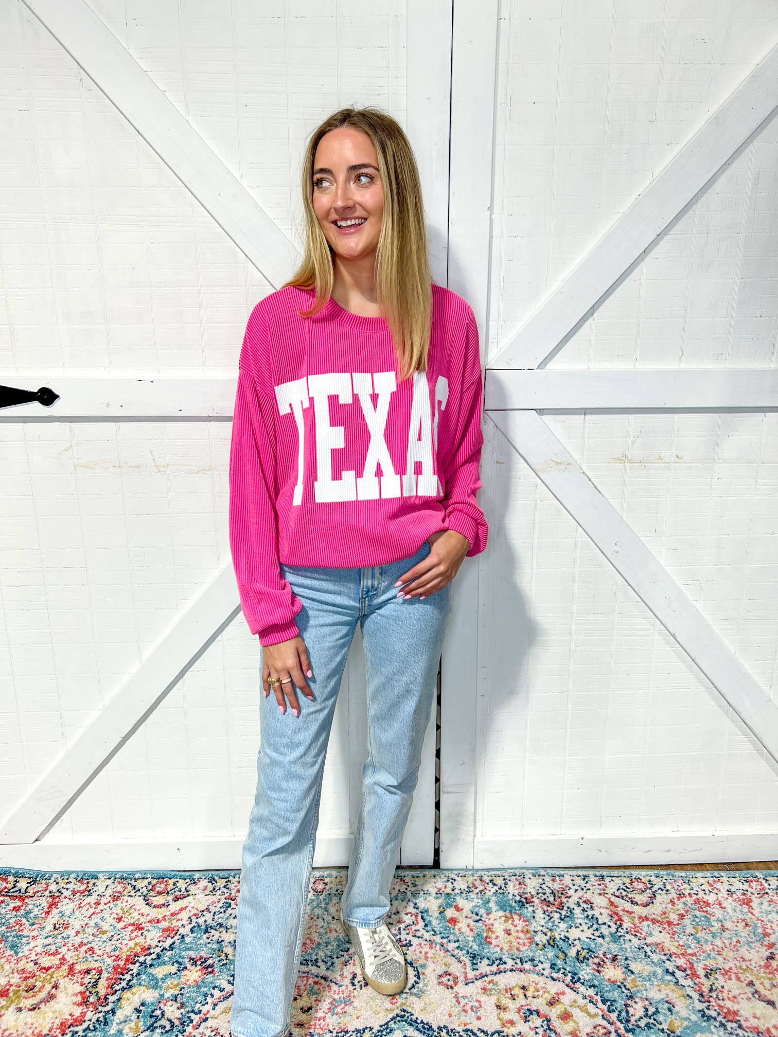 woman modeling our magenta Texas sweatshirt with large white bold letters saying TEXAS across the front