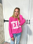 Closer view of a woman modeling our magenta Texas sweatshirt with large white bold letters saying TEXAS across the front