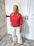 Another full length photo of model wearing a red 3/4 bubble sleeve top with horizontal light pink stripes