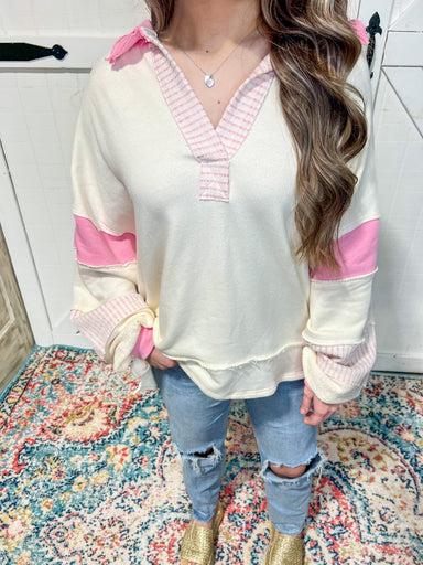 Up close photo of our off white v-neck sweatshirt with light pink stripes around the neck and bottom of sleeves