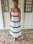 Woman modeling the back of this white sleeveless midi dress with wavy black occasional stripes made of ric rac material