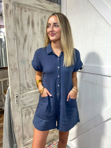 Up close photo of a woman wearing our navy short sleeve romper that has a collar, buttons up and has pockets