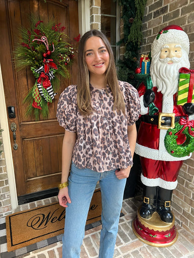 Woman standing in front of a decorated door with a large Santa Claus figure to her right.