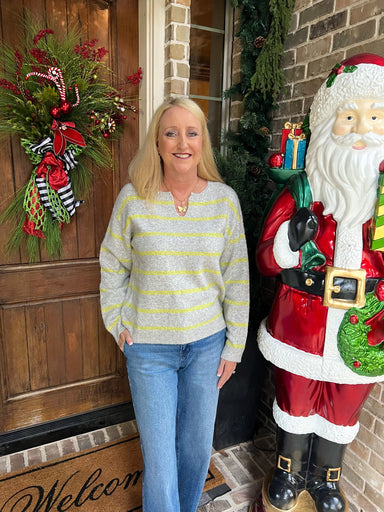 Woman wearing a thin and lightweight grey long sleeve sweater with lime green stripes