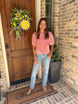 Woman standing in front of a door wearing an orange and white striped blouse