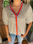 Up close photo of a cream and khaki striped short sleeve blouse with an orange and blue stripe around the collar and down the front 