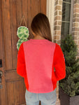 Photo of the back of this pink sweater with orange long sleeves