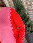Up close photo of a pink long sleeve sweater with orange sleeves