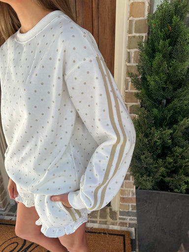 Up close photo of the polka dot long sleeve top showing the cream color with khaki dots and two stripes running down the side of the sleeves