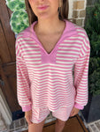 Up close photo of a woman wearing a pink and white striped long sleeve top with a v-neck