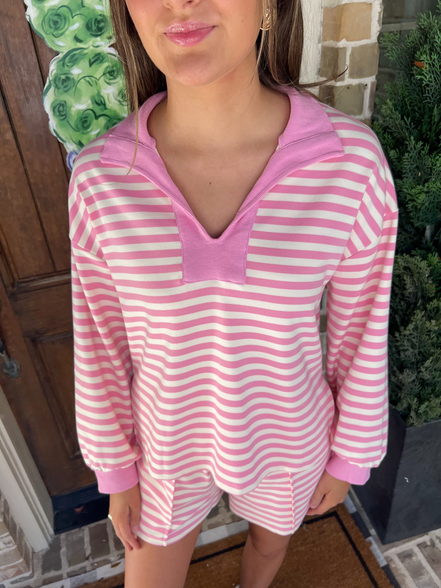 Up close photo of a woman wearing a pink and white striped long sleeve top with a v-neck