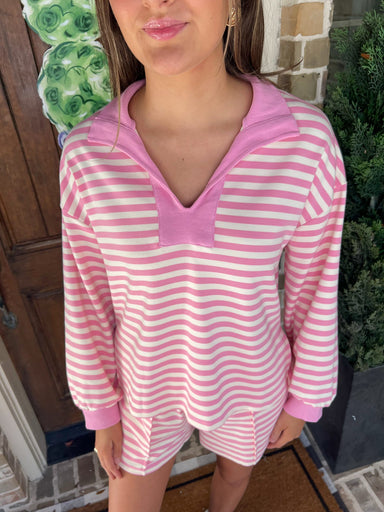Up close photo of a woman wearing a pink and white striped long sleeve top with a v-neck