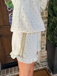 Up close photo of the polka dot shorts showing the cream color with khaki dots and two stripes running down the side of the shorts with a ruffle on the bottom