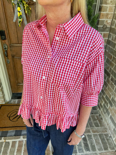 Person wearing a red and white checkered shirt standing in front of a door.
