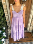 Person wearing a lavender dress standing on a doormat with 'home' written on it.