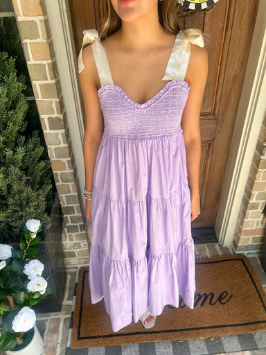 Person wearing a lavender dress standing on a doormat with 'home' written on it.