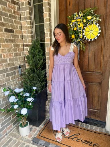 Wma modeling a lavender smocked midi dress that ties at the shoulders