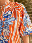 Up close photo of the blue embroidery on an orange striped blouse