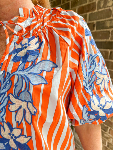 Up close photo of the blue embroidery on an orange striped blouse