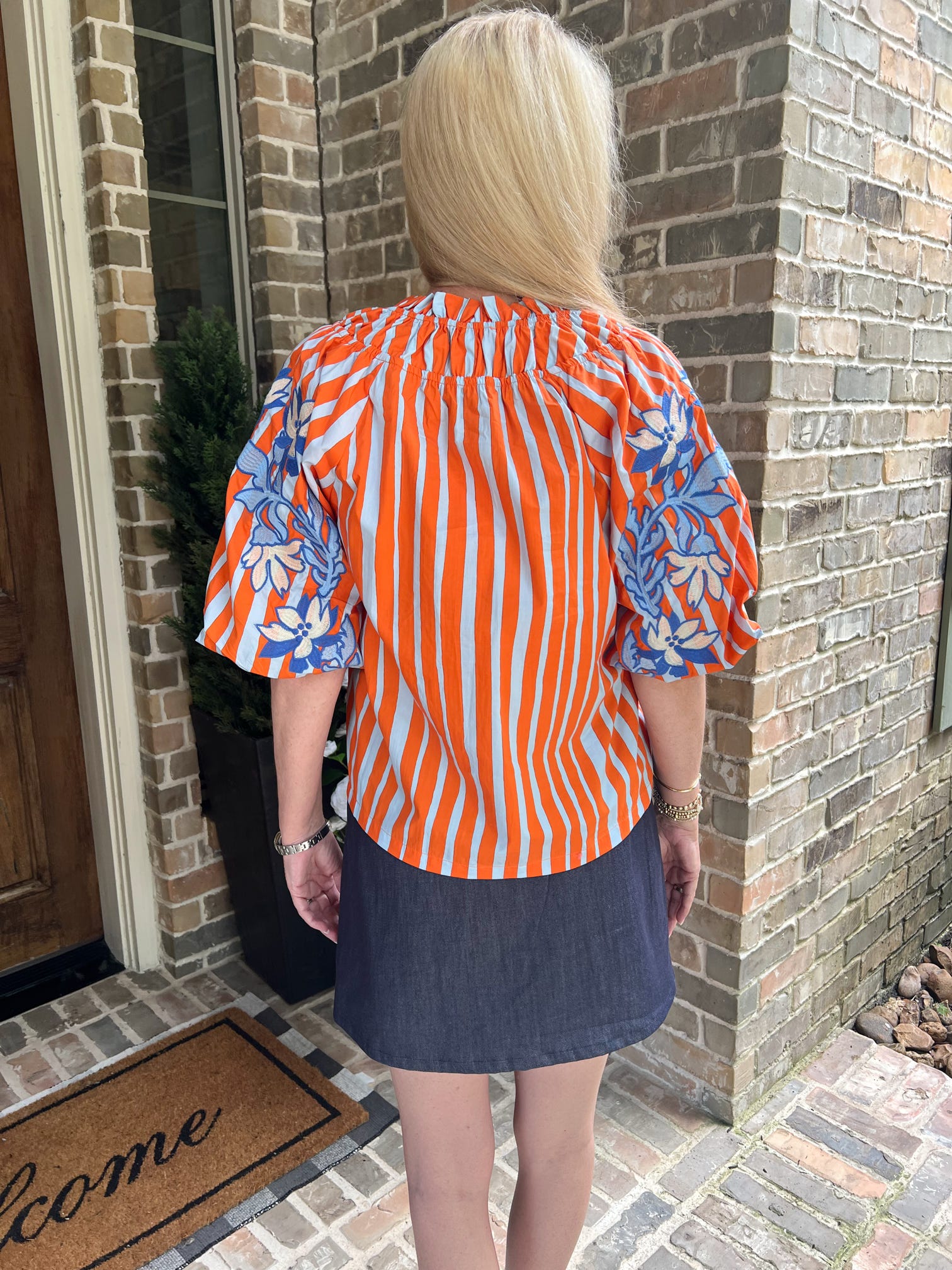 Photo of the back of an orange striped blouse with blue embroidered flowers