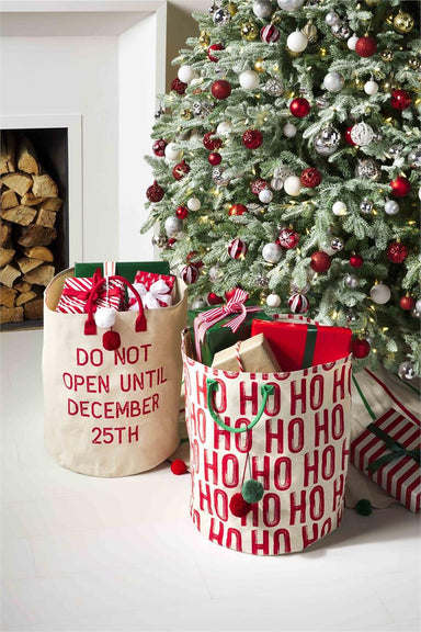 Photo of a Christmas tree with this large tote bag holding presents in front. Also in photo is it's matching tote bag saying Do Not Open Until December 25th