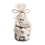 A black and white with a bow-shaped skull ceramic toothpick holder with 6 skull cardstock toppers on toothpicks in a clear bag with a decorative bow on a white background