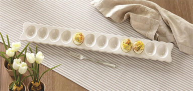 Staged photo of our long white deviled egg tray with silver fork on a dining table
