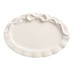 White decorative plate with a decorative edge and bow on a white background