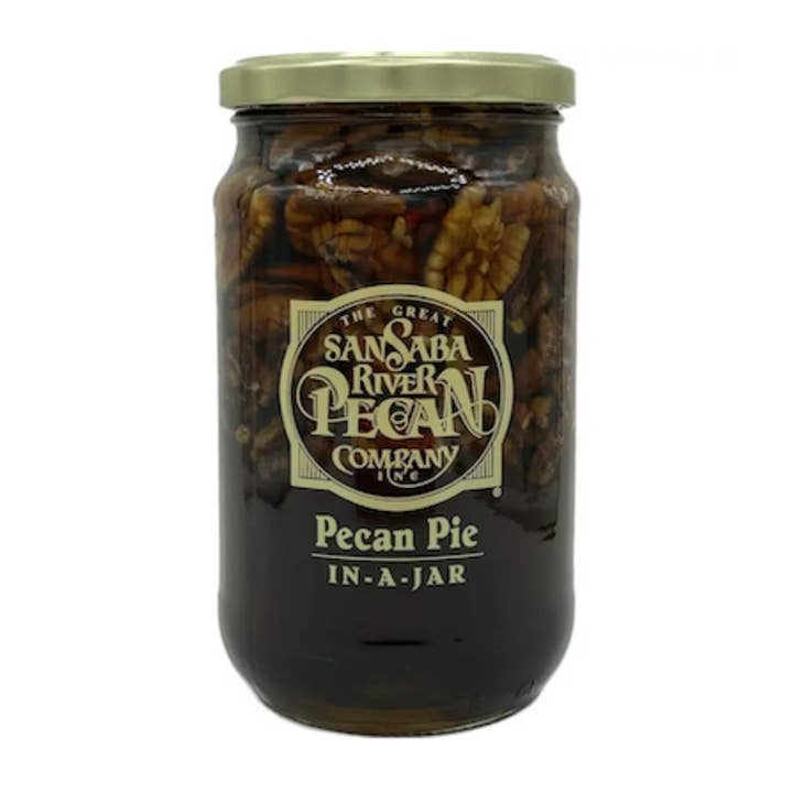 A glass jar of San Saba River Pecan Company 'In-A-Jar' Pecan Pie, filled with pecans in syrup and topped with a gold metal lid, shown against a plain white background.