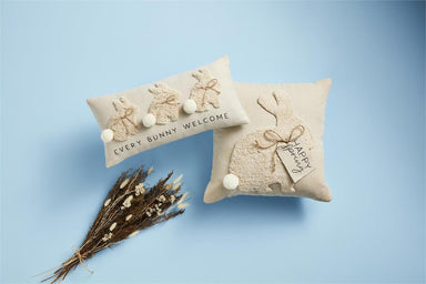 A staged photo showing our long bunny tufted pillow along with our square bunny tufted pillow and some dried flowers.