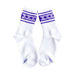 A pair of white crew socks with purple stripes and Greek lettering on the cuffs, displayed against a solid white background.