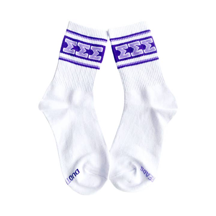A pair of white crew socks with purple stripes and Greek lettering on the cuffs, displayed against a solid white background.
