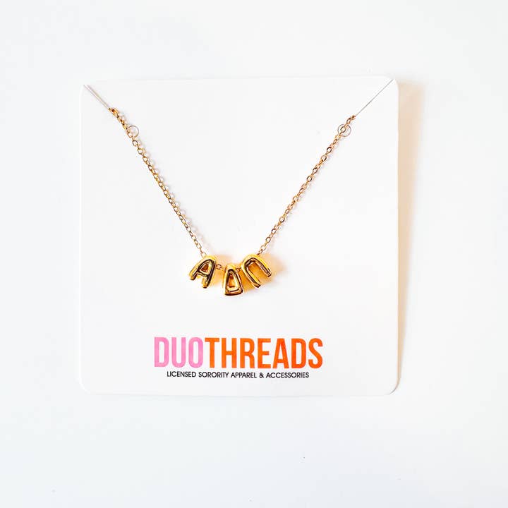 Gold necklace with 'ADPi' letters on a white background with 'DUO THREADS' branding.